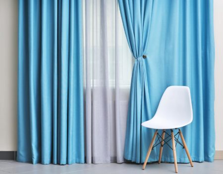 Chair and room window with white and blue curtains