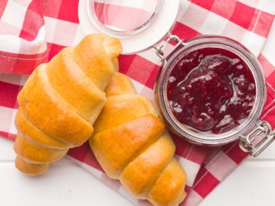 Sweet croissants and jam on checkered napkin.