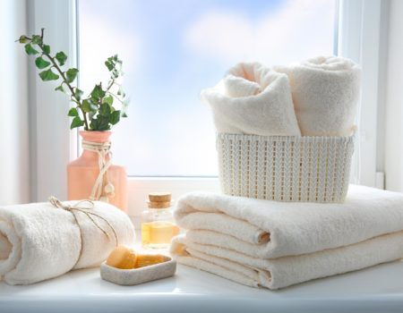 Folded towels stack,essential oil and soap on window sill empty copy space.Body care concept,hotel backdrop,bathroom items.