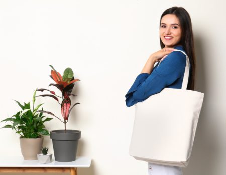 Beautiful young woman with stylish blank eco bag against color background